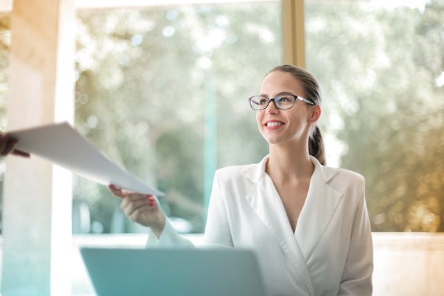 Person sitting in front of computer handing papers over