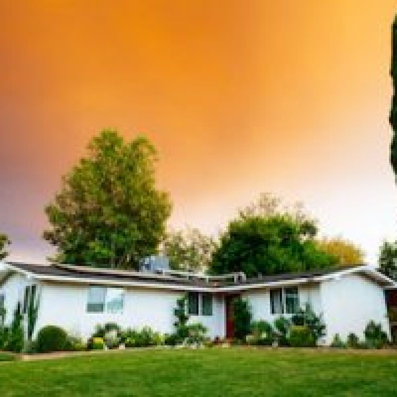 A home with trees and sunset in the background.